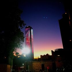 Low angle view of illuminated city against sky at night