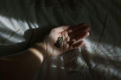 Cropped image of hand holding god figurine on bed at home