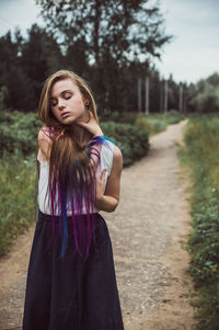 Portrait of beautiful young woman standing against trees