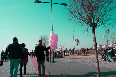 People on sidewalk in city against clear sky