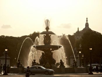 Statue against fountain in city against clear sky