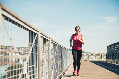 Full length of woman standing on bridge against sky