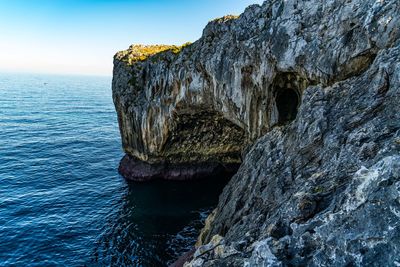 Rock formation in sea against sky