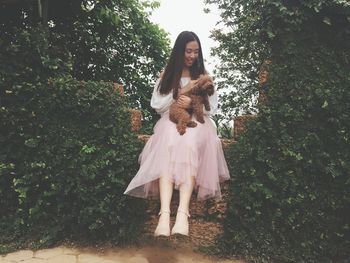 Portrait of young woman standing against trees