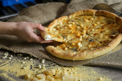 Cropped image of woman hand having pizza at table