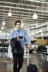 Businessman holding digital tablet while walking at airport