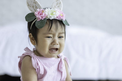 Close-up cute baby girl wearing headband crying at home