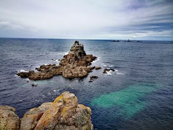 Rocks on sea shore against sky