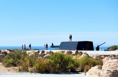 People at seaside against blue sky