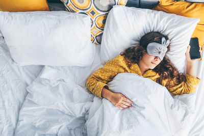 High angle view of woman using mobile phone on bed at home