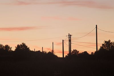 Silhouette electricity pylon against sky during sunset