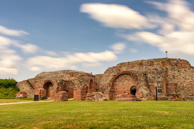 Old ruins in field against cloudy sky