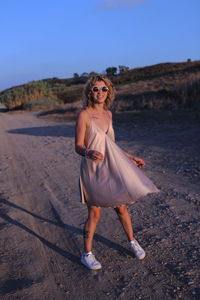 Portrait of smiling woman wearing sunglasses while walking on road