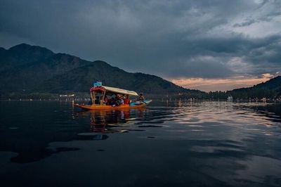 Boats moored in sea against cloudy sky