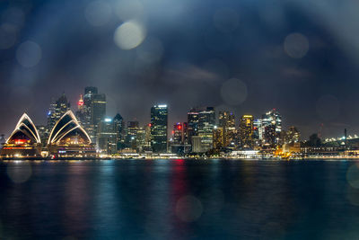 Illuminated buildings at waterfront during night