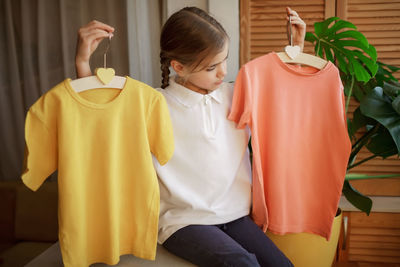 Girl chooses t-shirt among clothes at home. mockup friendly. t-shirts ready to have design