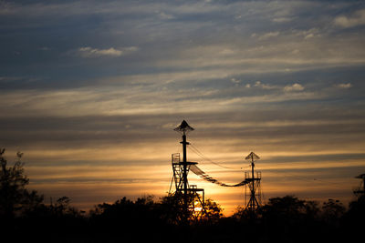 Silhouette electricity pylon against sky during sunset