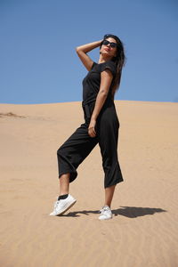 Full length of young woman standing on sand dune