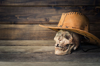 Close-up of artificial skull and hat on wooden table