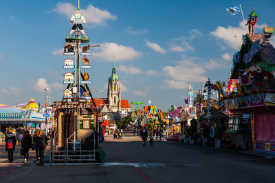 People at amusement park in city against sky