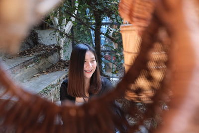 Portrait of smiling woman standing by tree