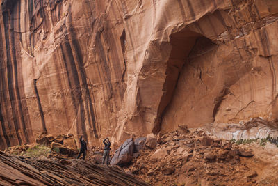 People below high sandstone canyon walls near escalante river, utah