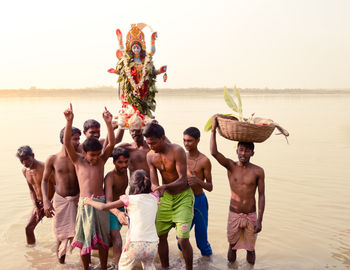 Group of people at beach against sky