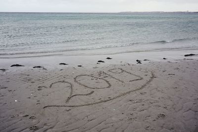 Heart shape on beach by sea against sky