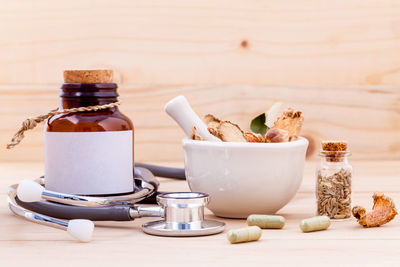 Medicines with spices and stethoscope on wooden table