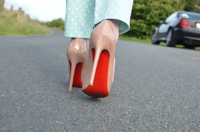 Low section of woman wearing high heels while walking on road