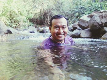 Portrait of happy young man swimming in river