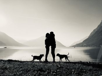 People with dog on mountain against sky