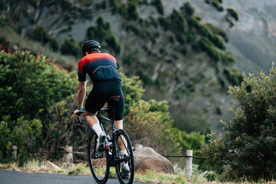 Rear view of man riding bicycle on mountain