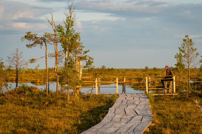 A woman sits on a specially equipped platform and admires the swamp landscape