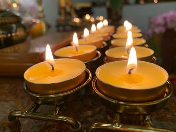 Close-up of lit tea light candles on table in temple