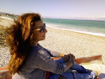 Side view of young woman sitting on beach