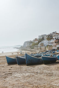 Boats moored on beach against clear sky