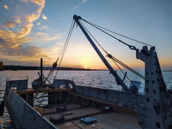 Ship returning to harbor against sky during sunset