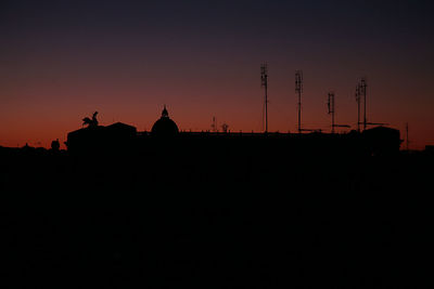 Silhouette people on cross against sky during sunset