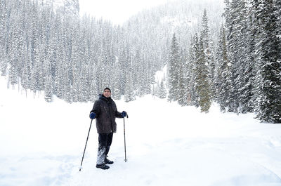 Man standing on snow covered field against trees