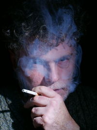 Close-up of hand holding smoke against black background