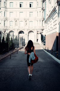 Rear view of woman walking on road in city