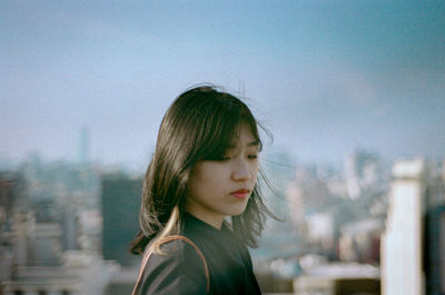 Woman looking down against buildings and sky in city