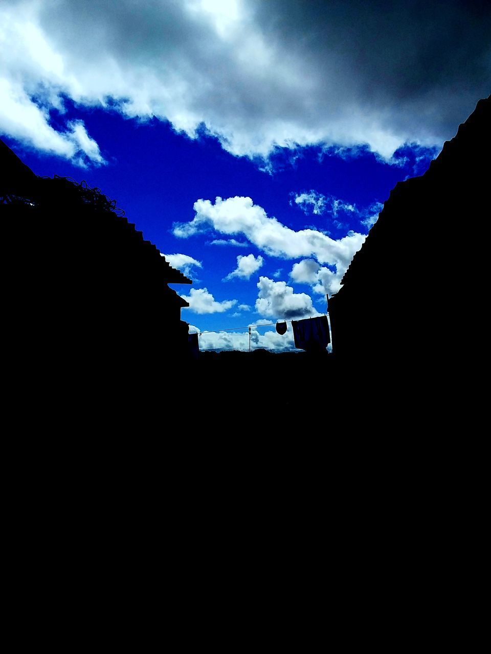 LOW ANGLE VIEW OF SILHOUETTE MOUNTAINS AGAINST BLUE SKY