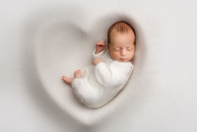 Portrait of cute baby boy lying on white background