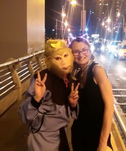 Portrait of young woman standing against wall at night