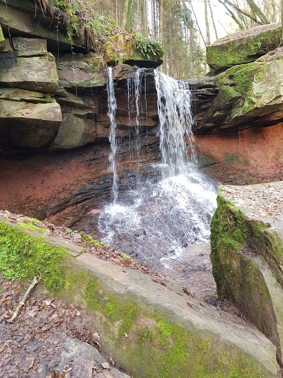 SCENIC VIEW OF WATERFALL AGAINST ROCKS IN FOREST