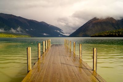 Wooden pier in lake against mountains