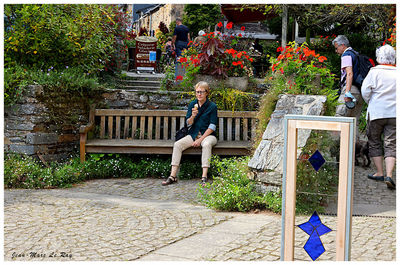 People sitting on bench against plants