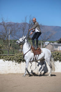 Full length of man standing on horse against sky